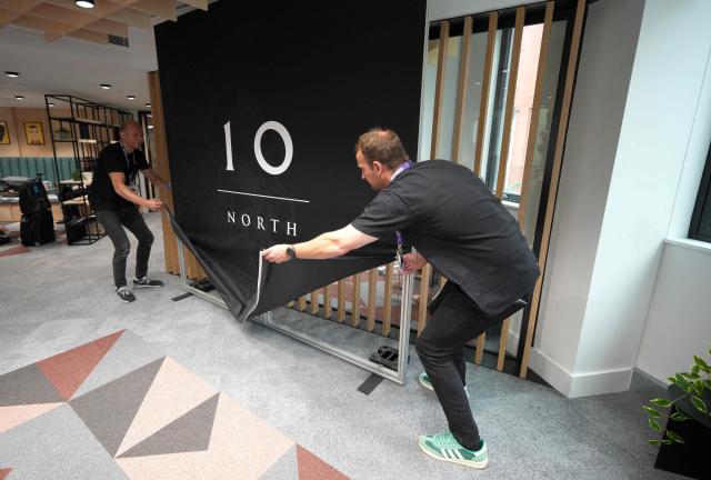 Government staff prepare a number 10 North sign for a media interview during a National Economic Council meeting at No 10 North at Heron House in Manchester, north-west England on July 24, 2026. British Prime Minister Andy Burnham opened his newly created northern office on Friday, as he bids to launch his flagship move to reverse decades of centralising power over England in London. (Photo by Christopher Furlong / POOL / AFP)