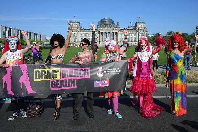 Participants react in front of the Reichstag building in Berlin, which houses Germany's Bundestag lower house of parliament, during the start of the Drag Queen March on July 24, 2026. Ahead of the Christopher Street Day (CSD) parade, Berlin hosts its first-ever Drag March bringing a tradition known from New York to Berlin. (Photo by RALF HIRSCHBERGER / AFP)