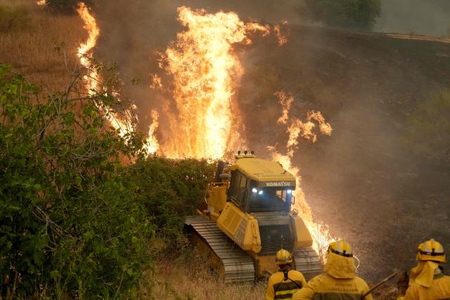 Firefighters battle a wildfire in Cebreros area, near Avila, 80 kms west of Madrid on July 24, 2026. Spain declared a national emergency in the Madrid region and in the province of Avila, near the capital, on July 23, 2026, in the wake of several wildfires burning out of control. Scientists have long warned that climatechange caused by human use of fossil fuels will make periods of drought more intense and longer-lasting, creating the ideal conditions for wildfires. (Photo by Cesar MANSO / AFP)