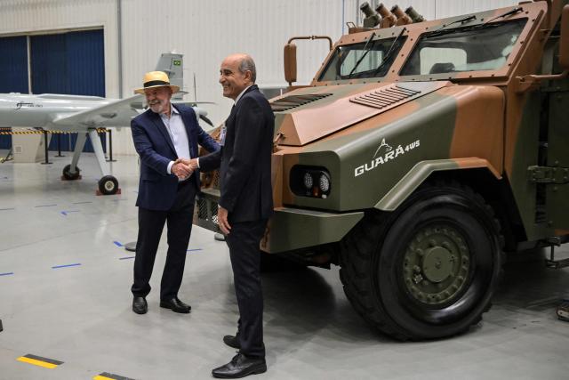 Brazil's President Luiz Inacio Lula da Silva (L) and the CEO of Brazilian defense and aerospace company Avibras Aeroco, Sami Hassuani (R), shake hands during a visit to the Avibras Aeroco headquarters, in Jacarei, some 90 km from Sao Paulo, Brazil, on July 24, 2026. (Photo by Nelson ALMEIDA / AFP)