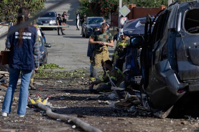Rescuers work around the wreck of a car at the site of a Russian missile strikes at an undisclosed location in Kyiv region on July 24, 2026, amid the Russian invasion of Ukraine. (Photo by Tetiana DZHAFAROVA / AFP)