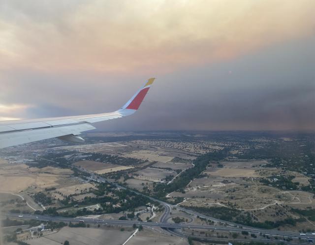 A picture taken on July 24, 2026 from a plane shows the smoke from a wildfire raging west of Madrid. The worst wildfires in the Madrid region's history rage west of the Spanish capital, forcing authorities to evacuate or order around 40,000 people to remain indoors. (Photo by Roland LLOYD PARRY / AFP)