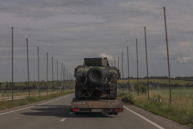 A truck transports a Humvee along a road covered with anti-drone nets in the eastern Kharkiv region on July 23, 2026, amid the Russian invasion of Ukraine. (Photo by Roman PILIPEY / AFP)