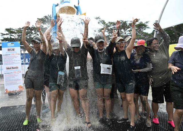 Tourists play with mud during the 29th Boryeong Mud Festival at Daecheon Beach in Boryeong on July 25, 2026, which runs from July 24 to August 9 and aims to promote the use of mud for cosmetic skincare and tourism in the region. (Photo by Jung Yeon-je / AFP)