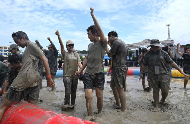 Tourists play with mud in a mud pool during the 29th Boryeong Mud Festival at Daecheon Beach in Boryeong on July 25, 2026, which runs from July 24 to August 9 and aims to promote the use of mud for cosmetic skincare and tourism in the region. (Photo by Jung Yeon-je / AFP)