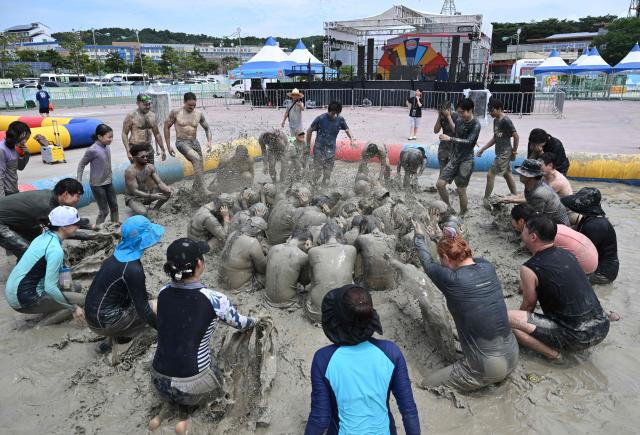 Tourists play with mud in a mud pool during the 29th Boryeong Mud Festival at Daecheon Beach in Boryeong on July 25, 2026, which runs from July 24 to August 9 and aims to promote the use of mud for cosmetic skincare and tourism in the region. (Photo by Jung Yeon-je / AFP)
