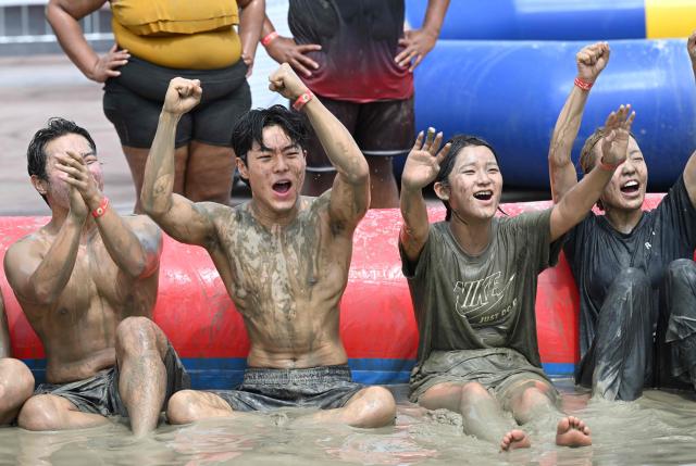 Tourists play with mud in a mud pool during the 29th Boryeong Mud Festival at Daecheon Beach in Boryeong on July 25, 2026, which runs from July 24 to August 9 and aims to promote the use of mud for cosmetic skincare and tourism in the region. (Photo by Jung Yeon-je / AFP)