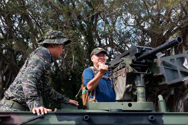 A Taiwanese soldier shows a visitor how to operate an MK19 Mod 3 40mm automatic grenade launcher mounted on a military vehicle during an open day at the National Defence University’s Fuxinggang campus in Taipei on July 25, 2026. (Photo by CHENG Yu-chen / AFP)