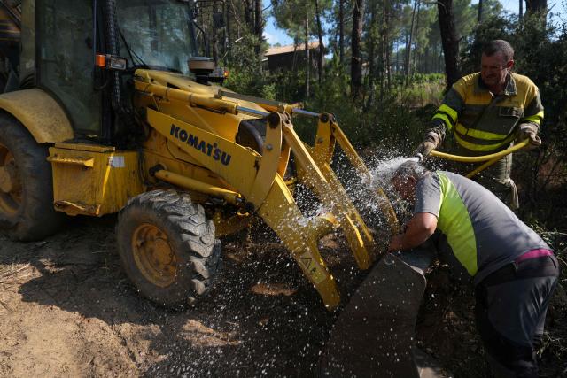 The driver of a bulldozer cools off while working at making a firestop in La Atalaya residential area in El Tiemblo, 80 kms west of Madrid, on July 25, 2026 amid wildfires that have burned up to 25,000 hectares. Spanish firefighters hoped to get control of wildfires raging near Madrid on Saturday but an official warned that erratic winds threatened to fan the blazes further. The worst wildfires in the Madrid region's history rage west of the Spanish capital, forcing authorities to evacuate or order around 60,000 people to remain indoors. (Photo by Cesar MANSO / AFP)