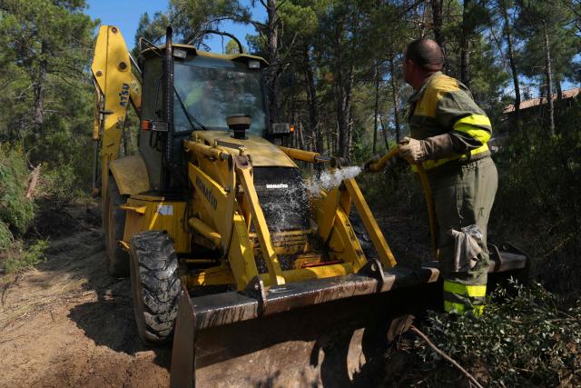 An emergency staff's member cools off a bulldozer's engine during works to make a firestop in La Atalaya residential area in El Tiemblo, 80 kms west of Madrid, on July 25, 2026 amid wildfires that have burned up to 25,000 hectares. Spanish firefighters hoped to get control of wildfires raging near Madrid on Saturday but an official warned that erratic winds threatened to fan the blazes further. The worst wildfires in the Madrid region's history rage west of the Spanish capital, forcing authorities to evacuate or order around 60,000 people to remain indoors. (Photo by Cesar MANSO / AFP)