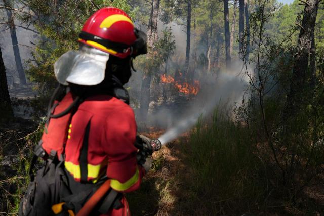 A Spain's Military Emergencies Unit (UME) firefighter battles a fire in a forest next to La Atalaya residential area in El Tiemblo, 80 kms west of Madrid, on July 25, 2026 amid wildfires that have burned up to 25,000 hectares. Spanish firefighters hoped to get control of wildfires raging near Madrid on Saturday but an official warned that erratic winds threatened to fan the blazes further. The worst wildfires in the Madrid region's history rage west of the Spanish capital, forcing authorities to evacuate or order around 60,000 people to remain indoors. (Photo by Cesar MANSO / AFP)