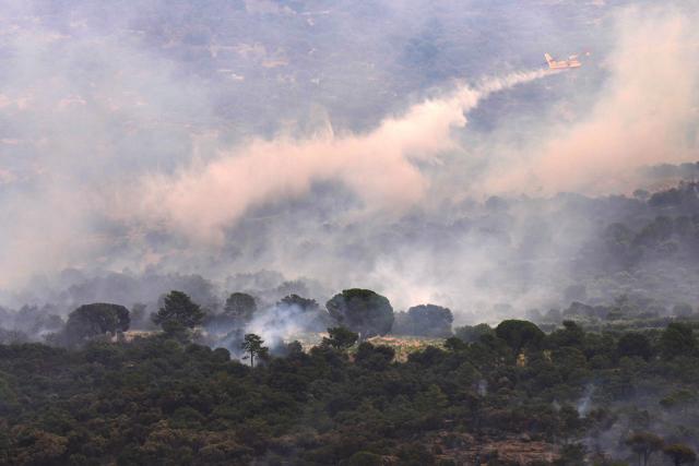 A picture taken on July 25, 2026 from El Tiemblo, 80 kms west of Madrid, shows a plane dumping water to battle wildfire between El Tiemblo and San Martin de Valdeiglesias. Spanish firefighters hoped to get control of wildfires raging near Madrid on Saturday but an official warned that erratic winds threatened to fan the blazes further. The worst wildfires in the Madrid region's history rage west of the Spanish capital, forcing authorities to evacuate or order around 60,000 people to remain indoors. (Photo by Cesar MANSO / AFP)