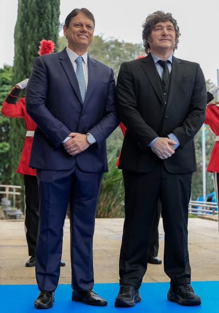 Argentina's President Javier Milei (R) and Sao Paulo's governor Tarcisio de Freitas stand in front of a guard of honour at the Bandeirantes Palace, in Sao Paulo, Brazil on July 25, 2026. Milei is visiting Brazil to meet with right-wing presidential hopeful Flavio Bolsonaro and take part in the Liberal Party convention that supports his candidacy, (Photo by Miguel SCHINCARIOL / AFP)