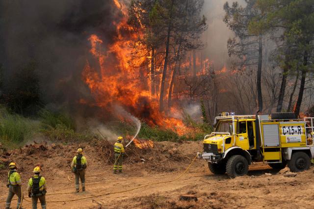 Castilla-y-Leon district's firefighters battle a fire surrounding La Atalaya residential area in El Tiemblo, 80 kms west of Madrid, on July 25, 2026 amid wildfires that have burned up to 25,000 hectares. Spanish firefighters hoped to get control of wildfires raging near Madrid on Saturday but an official warned that erratic winds threatened to fan the blazes further. The worst wildfires in the Madrid region's history rage west of the Spanish capital, forcing authorities to evacuate or order around 60,000 people to remain indoors. (Photo by Cesar MANSO / AFP)