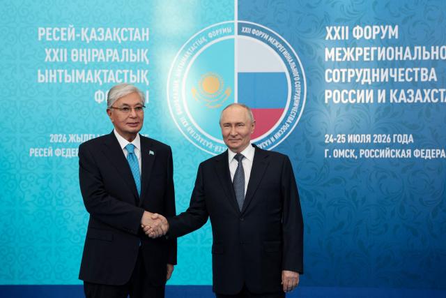 In this pool photograph distributed by the Russian state agency Sputnik, Russia's President Vladimir Putin (R) greets Kazakhstan's President Kassym-Jomart Tokayev during the 22nd Russia-Kazakhstan Forum of Interregional Cooperation in Omsk on July 25, 2026. (Photo by Vyacheslav PROKOFYEV / POOL / AFP)
