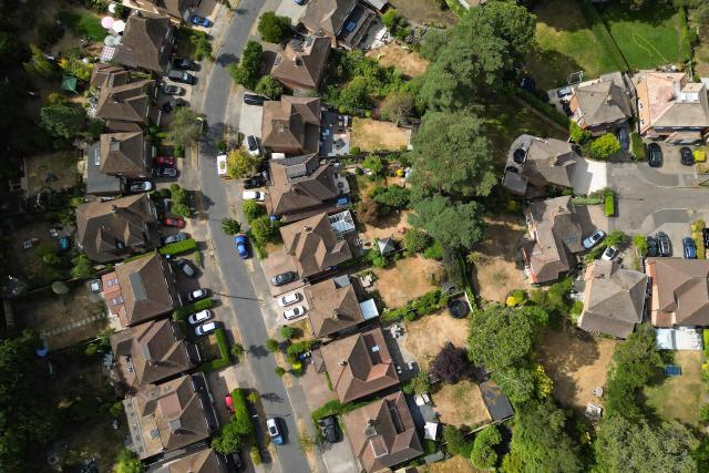 An aerial view shows parched gardens with dried and yellowed grass on residential streets in Woking , west of London on July 25, 2026, during the extended heatwave. Several areas of southern England were at "exceptional" risk of major wildfires, according to government advisory body Natural England, as Britain has faced unprecedented heatwaves for much of the last two months. (Photo by Justin TALLIS / AFP)