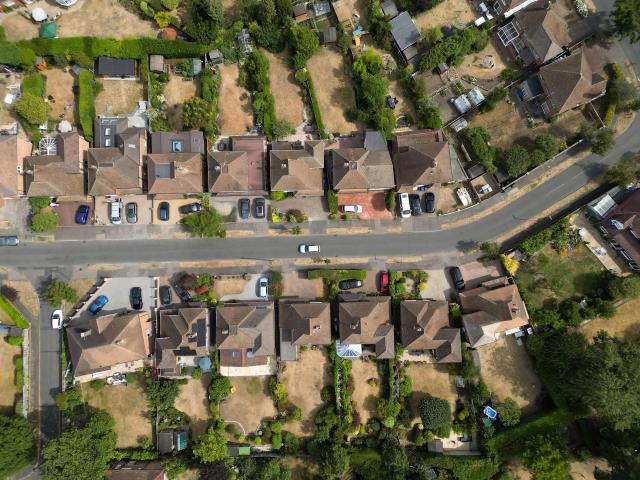 An aerial view shows parched gardens with dried and yellowed grass on residential streets in Woking , west of London on July 25, 2026, during the extended heatwave. Several areas of southern England were at "exceptional" risk of major wildfires, according to government advisory body Natural England, as Britain has faced unprecedented heatwaves for much of the last two months. (Photo by Justin TALLIS / AFP)