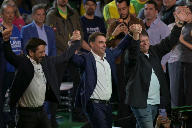 Brazil's right-wing presidential hopeful Flavio Bolsonaro (C), Sao Paulo's mayor Ricardo Nunes (L) and Sao Paulo's governor Tarcisio de Freitas wave during the Liberal Party (PL) convention, in Sao Paulo, Brazil on July 25, 2026. Battered by a string of political crises, Flavio Bolsonaro will launch his candidacy for Brazil's October presidential election, seeking to follow in the footsteps of his father, Jair Bolsonaro. (Photo by Nelson ALMEIDA / AFP)