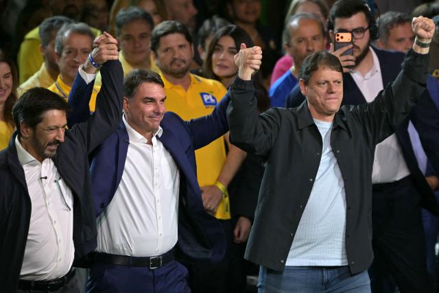 Brazil's right-wing presidential hopeful Flavio Bolsonaro (C), Sao Paulo's mayor Ricardo Nunes (L) and Sao Paulo's governor Tarcisio de Freitas wave during the Liberal Party (PL) convention, in Sao Paulo, Brazil on July 25, 2026. Battered by a string of political crises, Flavio Bolsonaro will launch his candidacy for Brazil's October presidential election, seeking to follow in the footsteps of his father, Jair Bolsonaro. (Photo by Nelson ALMEIDA / AFP)