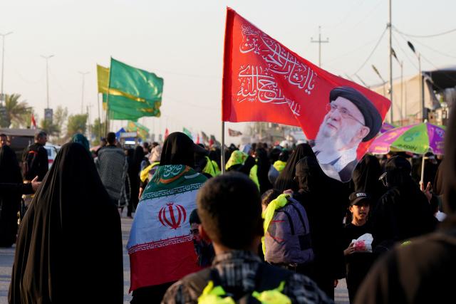 Iranian pilgrims walk along the highway from the holy Shia Muslim city of Najaf to Karbala, some 80 kilometers away, as they march to commemorate the Arbaeen or 40 days of mourning after the martyrdom in the Battle of Karbala in 680 CE of Imam Hussein, the grandson of the Prophet Muhammad, on July 25, 2026. Over the past two days, thousands of Iranian pilgrims have arrived in the city of Najaf before heading on foot to the holy city of Karbala to commemorate the Arbaeen of Imam Hussein, carrying Iranian flags and portraits of former Iranian Supreme Leader Ayatollah Ruhollah Khomeini, Supreme Leader Ali Khamenei (on the flag), and Mojtaba Khamenei. The arrival of Iranian pilgrims in Iraq comes despite the ongoing war between the US and Iran, as pilgrims continue their journey toward Karbala to participate in the Arbaeen pilgrimage. (Photo by Qassem al-KAABI / AFP)