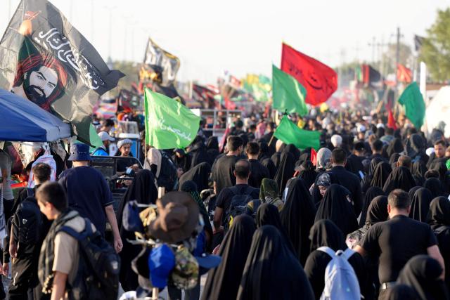 Iranian pilgrims walk along the highway from the holy Shia Muslim city of Najaf to Karbala, some 80 kilometers away, as they march to commemorate the Arbaeen or 40 days of mourning after the martyrdom in the Battle of Karbala in 680 CE of Imam Hussein, the grandson of the Prophet Muhammad, on July 25, 2026. Over the past two days, thousands of Iranian pilgrims have arrived in the city of Najaf before heading on foot to the holy city of Karbala to commemorate the Arbaeen of Imam Hussein, carrying Iranian flags and portraits of former Iranian Supreme Leader Ayatollah Ruhollah Khomeini, Supreme Leader Ali Khamenei, and Mojtaba Khamenei. The arrival of Iranian pilgrims in Iraq comes despite the ongoing war between the US and Iran, as pilgrims continue their journey toward Karbala to participate in the Arbaeen pilgrimage. (Photo by Qassem al-KAABI / AFP)