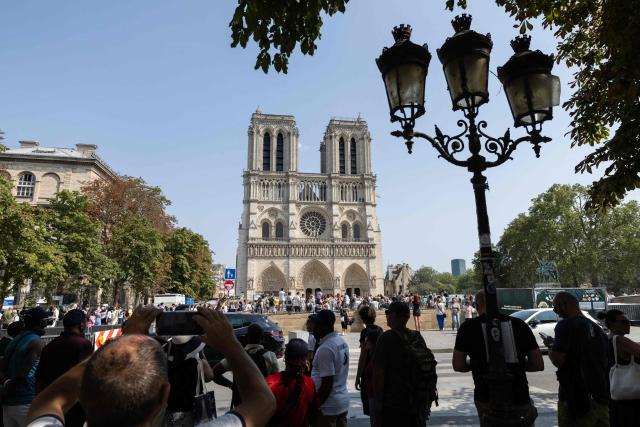 Tourists stand in a shaded area in front of Notre-Dame Cathedral during a hot summer day in Paris on July 25, 2026. (Photo by Xavier GALIANA / AFP)