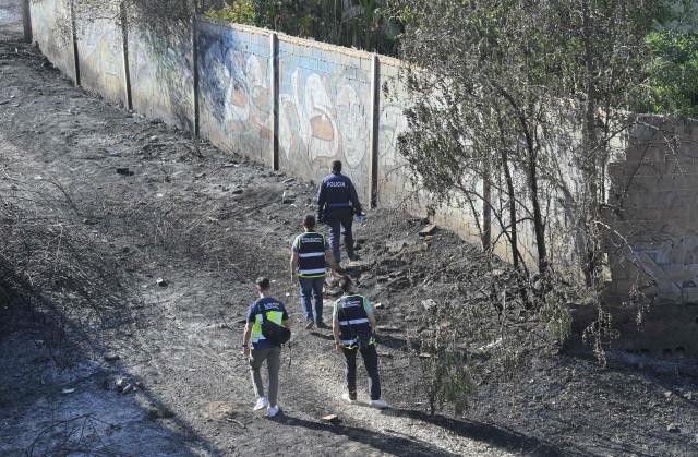 Spain's national police officers inspect after battling a fire that killed one person, in a area of vegetables garden and orchards in a gorge of Manises, eastern Spain, on July 25, 2026. A fire in a ravine near Valencia, in the east of Spain, killed one person, according to the local authority in the affected town of Manises. (Photo by Jose JORDAN / AFP)