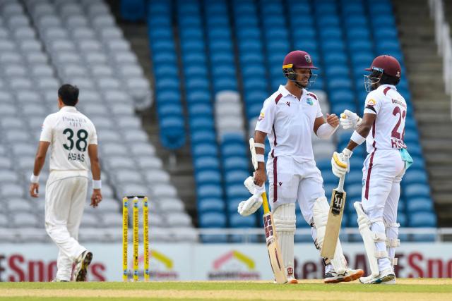 Tagenarine Chanderpaul (2nd R) and Kavem Hodge (R) of West Indies knock gloves as Mohammad Abbas (L) of Pakistan goes back to bowl during the first day of first Test match between West Indies and Pakistan at Brian Lara Cricket Academy in Tarouba, Trinidad and Tobago, on July 25, 2026. (Photo by Randy Brooks / AFP)