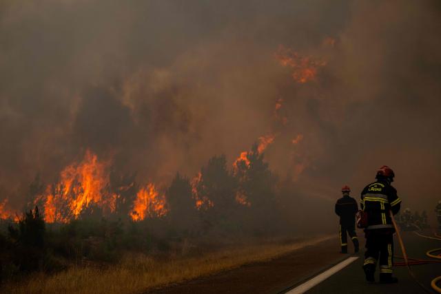 Firefighters spray water along the edge of a forest during a wildfire near the town of Lege-Cap-Ferret, in southwestern France on July 25, 2026. Fires are raging on July 25, 2026 in France and Spain, with nearly 260,000 people evacuated near the big French city of Bordeaux and in the Madrid region, a metropolis confronted with the "worst" fire in its history. Scientists have long warned that climate change caused by human use of fossil fuels will make periods of drought more intense and longer-lasting, creating the ideal conditions for wildfires. (Photo by JULIEN DE ROSA / AFP)