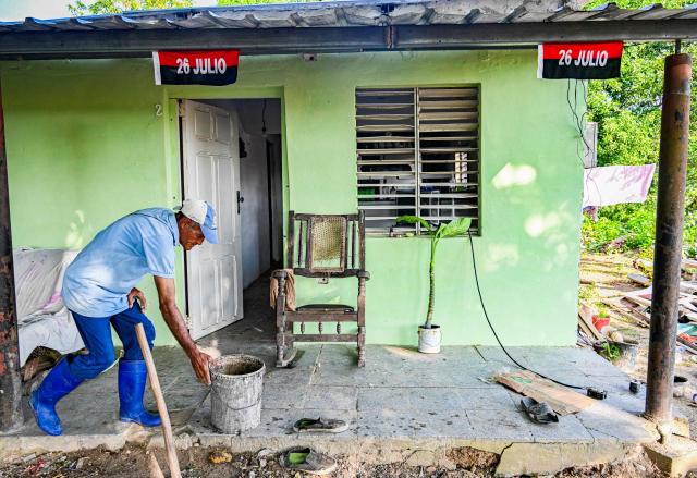 A farmer decorates the front of his rural house with flags of the July 26 Movement --once led by the late leader Fidel Castro-- in Pinar del Rio, Cuba, on July 25, 2026, on the eve of the 73rd anniversary of the guerrilla assault on the Moncada Barracks, considered the start of the Cuban Revolution. (Photo by YAMIL LAGE / AFP)