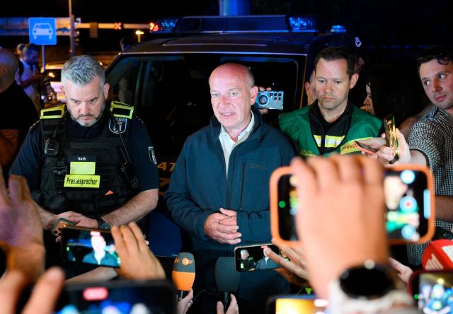 Berlin's mayor Kai Wegner (C) speaks to the media as Police spokesman Florian Nath (L) listens near the scene where one person was killed and around 15 injured after a car is believed to have hit the crowd on the outskirts of the Christopher Street Day (CSD) parade in Berlin, on July 25, 2026. "We believe that a vehicle entered the Tiergarten park and hit several people and injured them," police posted on social media. The injured were being treated by the emergency services and they were actively seeking the people responsible, they added. (Photo by RALF HIRSCHBERGER / AFP)