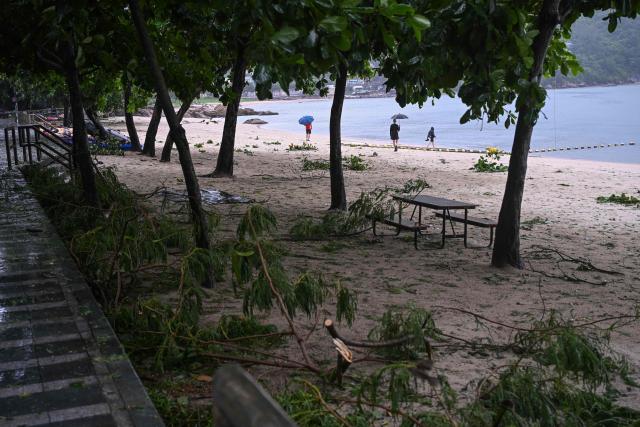 People walk on a beach with debris from Typhoon Noul which passed close to Hong Kong on July 26, 2026. (Photo by Peter PARKS / AFP)