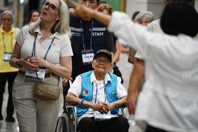 Philippines veteran of the Korean War Rodrigo Cruz Erenio  listens to a guide during a visit to the Korean War Memorial in Seoul on July 26, 2026. Seventy-four participants from 21 countries, including 13 UN Korean War veterans and bereaved family members are visiting Seoul as part of the Revisit Korea Program for UN Korean War Veterans. (Photo by GREG BAKER / AFP)