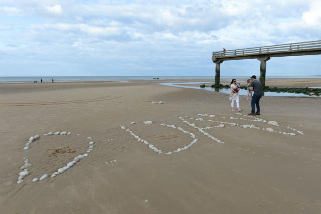 (FILES) A family stands next to the word "D-Day" written with stones on "Omaha Beach", in Vierville-sur-Mer, northwestern France, during the preparations of the celebrations marking the 75th anniversary of D-Day landings. Several D-Day landing beaches have been added to UNESCO’s World Heritage List on July 26, 2026, the culmination of a project launched nearly 20 years ago that could boost tourism. (Photo by JEAN-FRANCOIS MONIER / AFP)