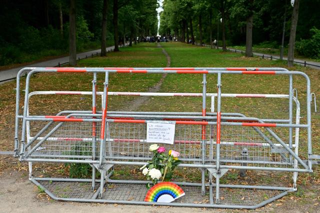 A, inscription reading "We need to stick together! Together we are stronger than hate and violence" has been attached on a barrier next to a bouquet of flowers and a rainbow colloured fan in commemoration for the victims on July 26, 2026 near the site in the Tiergarten park in Berlin, where a car was driven the evening before into people killing one person and injuring 16 on the outskirts of the Christopher Street Day (CSD) parade. German police searched on July 26, 2026 for a suspect believed linked to Islamist circles after a car ploughed into a crowd near Berlin's Gay Pride celebrations, killing one person and wounding 16 others. The incident shattered what had been a day of celebration for hundreds of thousands attending Christopher Street Day, one of Europe's largest Pride events, and left revellers fleeing a central Berlin park as sirens echoed through the night. (Photo by John MACDOUGALL / AFP)