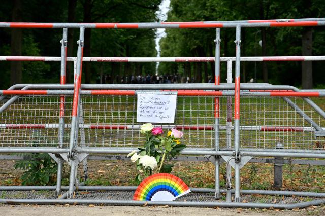 A, inscription reading "We need to stick together! Together we are stronger than hate and violence" has been attached on a barrier next to a bouquet of flowers and a rainbow colloured fan in commemoration for the victims on July 26, 2026 near the site in the Tiergarten park in Berlin, where a car was driven the evening before into people killing one person and injuring 16 on the outskirts of the Christopher Street Day (CSD) parade. German police searched on July 26, 2026 for a suspect believed linked to Islamist circles after a car ploughed into a crowd near Berlin's Gay Pride celebrations, killing one person and wounding 16 others. The incident shattered what had been a day of celebration for hundreds of thousands attending Christopher Street Day, one of Europe's largest Pride events, and left revellers fleeing a central Berlin park as sirens echoed through the night. (Photo by John MACDOUGALL / AFP)