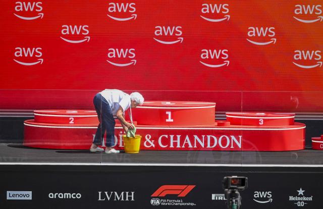 An elderly woman cleans the podium ahead of the Formula One Hungarian Grand Prix at the Hungaroring racetrack in Mogyorod near Budapest, Hungary, on July 26, 2026. (Photo by Attila KISBENEDEK / AFP)