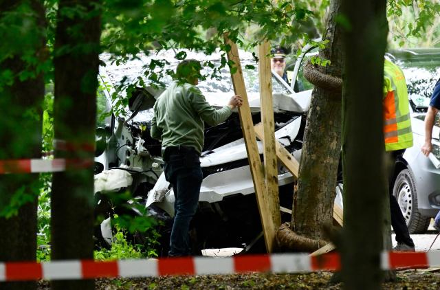 Police officers remove on July 26, 2026 planks of wood that were stuck in the car that alledgedly was driven into people killing one person and injuring 16 before crashing on a tree in the Tiergarten park on the outskirts of the Christopher Street Day (CSD) parade in Berlin held the day before. German police searched on July 26, 2026 for a suspect believed linked to Islamist circles after a car ploughed into a crowd near Berlin's Gay Pride celebrations, killing one person and wounding 16 others. The incident shattered what had been a day of celebration for hundreds of thousands attending Christopher Street Day, one of Europe's largest Pride events, and left revellers fleeing a central Berlin park as sirens echoed through the night. (Photo by John MACDOUGALL / AFP)