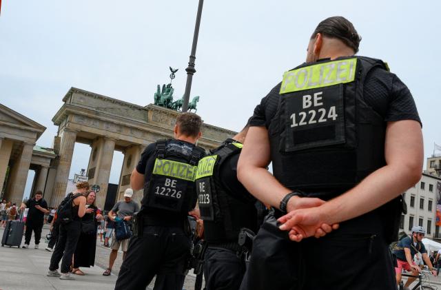 Police stand guard on July 26, 2026 in front of landmark Brandenburg Gate before to a so-called "community mourning" one day after the car ramming attack on people on the outskirts of Berlin's Christopher Street Day (CSD) parade on late July 25, 2026, killing one person and injuring 16 in the Tiergarten park. German police searched on July 26, 2026 for a suspect believed linked to Islamist circles after a car ploughed into a crowd near Berlin's Gay Pride celebrations, killing one person and wounding 16 others. The incident shattered what had been a day of celebration for hundreds of thousands attending Christopher Street Day, one of Europe's largest Pride events, and left revellers fleeing a central Berlin park as sirens echoed through the night. (Photo by RALF HIRSCHBERGER / AFP)