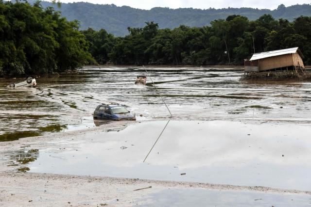 Cars are seen trapped in mud following flash floods owing to heavy rain at a village in Assam's Sivasagar district on July 26, 2026. (Photo by Biju BORO / AFP)