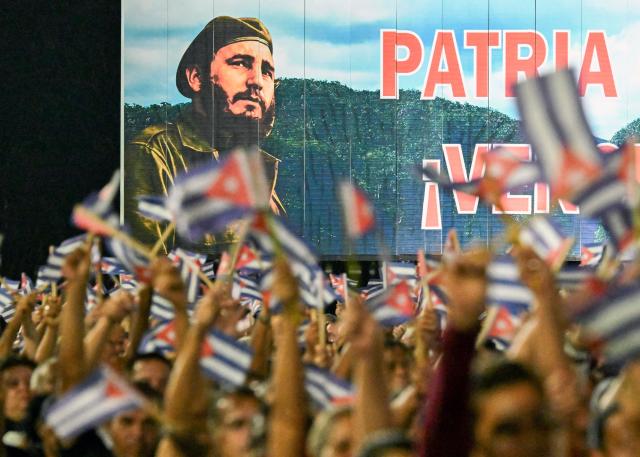 Cubans wave paper flags in front of a billboard depicting the late leader Fidel Castro during the 73rd anniversary celebration of the guerrilla assault on the Moncada Barracks, led by Fidel Castro and considered the start of the Cuban Revolution, in Pinar del Rio, Cuba, on July 26, 2026. (Photo by YAMIL LAGE / AFP)