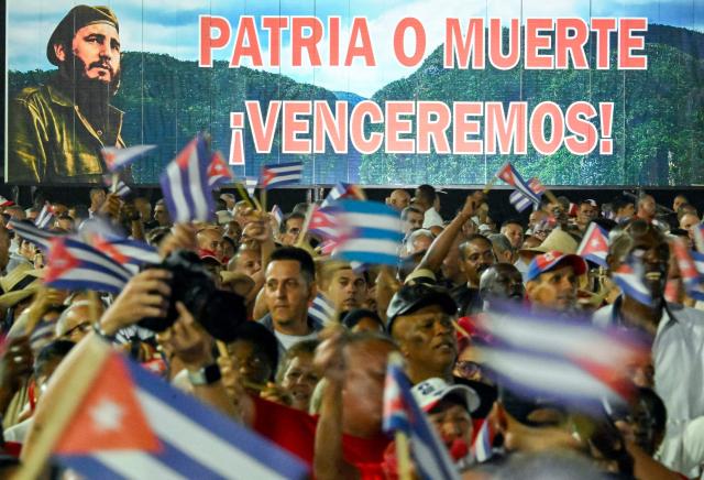 Cubans wave paper flags in front of a billboard depicting the late leader Fidel Castro and reading "Homeland or death, we will defeat!" during the 73rd anniversary celebration of the guerrilla assault on the Moncada Barracks, led by Fidel Castro and considered the start of the Cuban Revolution, in Pinar del Rio, Cuba, on July 26, 2026. (Photo by YAMIL LAGE / AFP)