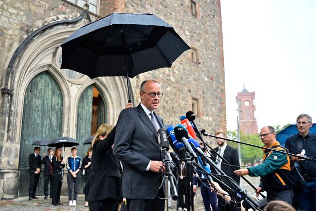 German Chancellor Friedrich Merz gives a press statement on July 26, 2026 in front of the Marienkirche church in Berlin and with Berlin's city Hall (Rotes Rathaus) in the background (R), about the deadly car-ramming attack in the Tiergarten park that left one woman dead and 29 other people injured on the sidelines of the Christopher Street Day (CSD) parade the evening before. German police on July 26, 2026 were hunting for the prime suspect in what authorities called an Islamist terror attack on the outskirts of Berlin Pride late on July 25, 2026. The incident shattered what had been a day of celebration for hundreds of thousands attending Christopher Street Day (CSD), one of Europe's largest Pride events. (Photo by John MACDOUGALL / AFP)