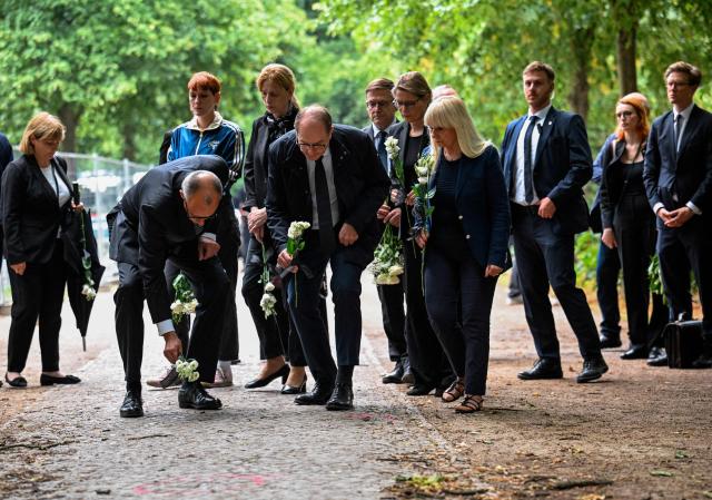 TOPSHOT - German Chancellor Friedrich Merz (3rd L) and German Interior Minister Alexander Dobrindt (4thL) lay flowers on July 26, 2026 the site in Tiergarten park in Berlin where a vehicle crashed into a crowd near Berlin's annual Christopher Street Day Pride parade on the evening of June 25, leaving one woman dead and multiple people injured. German police searched on July 26, 2026 for a suspect believed linked to Islamist circles after a car ploughed into a crowd near Berlin's Gay Pride celebrations, killing one person and wounding 29 others. The incident shattered what had been a day of celebration for hundreds of thousands attending Christopher Street Day, one of Europe's largest Pride events, and left revellers fleeing a central Berlin park as sirens echoed through the night. (Photo by Annegret Hilse / POOL / AFP)