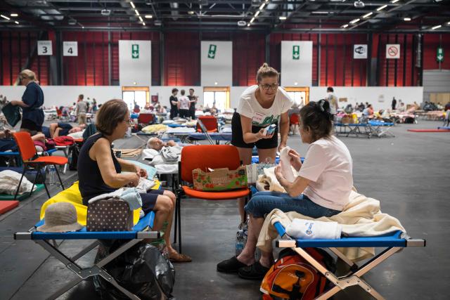 A staff member hands out supplies at an exhibition centre being used for people displaced by the wildfires, in Bordeaux, southwestern France on July 26, 2026. France fought an "unpredictable" wildfire close to Bordeaux on July 26, 2026 while Spain warned of "difficult hours" in its own fiery battle, with evacuations from danger zones in both countries mounting to well over 300,000 people. Scientists have long warned that climate change caused by human use of fossil fuels will make periods of drought more intense and longer-lasting, creating the ideal conditions for wildfires. (Photo by Ed JONES / AFP)