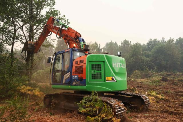An excavator tears out trees to construct a firebreak in a forest near Cestas, some 17km from Bordeaux, on July 26, 2026 as a wildfire has been ravaging the forest north of the Arcachon Basin (Gironde). The 220,000 people evacuated due to the massive wildfire in France's Gironde region will not be able to return home "until the fire has been brought under control", the local prefect said, also ruling out any normal workday on Monday in the affected towns, ahead of a possible worsening of the situation on Tuesday due to an expected rise in temperatures. (Photo by ROMAIN PERROCHEAU / AFP)