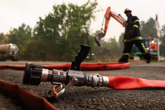 A firefighter walks past a fire hose in a forest near Cestas, some 17km from Bordeaux, on July 26, 2026 as a wildfire has been ravaging the forest north of the Arcachon Basin (Gironde). The 220,000 people evacuated due to the massive wildfire in France's Gironde region will not be able to return home "until the fire has been brought under control", the local prefect said, also ruling out any normal workday on Monday in the affected towns, ahead of a possible worsening of the situation on Tuesday due to an expected rise in temperatures. (Photo by ROMAIN PERROCHEAU / AFP)