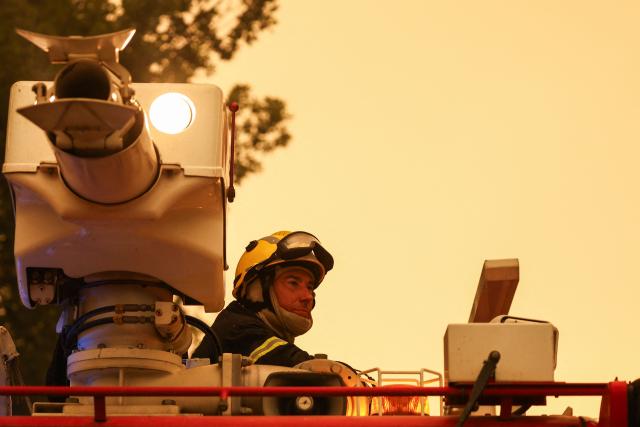 A firefighter looks on from a fire truck in a forest near Cestas, some 17km from Bordeaux, on July 26, 2026 as a wildfire has been ravaging the forest north of the Arcachon Basin (Gironde). The 220,000 people evacuated due to the massive wildfire in France's Gironde region will not be able to return home "until the fire has been brought under control", the local prefect said, also ruling out any normal workday on Monday in the affected towns, ahead of a possible worsening of the situation on Tuesday due to an expected rise in temperatures. (Photo by ROMAIN PERROCHEAU / AFP)