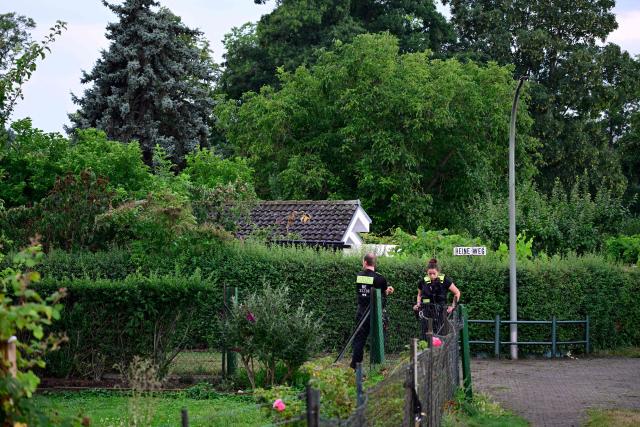 Police officers are seen in an allotment complex in the western Spandau district of Berlin on July 26, 2026, in the garden area near where the chief suspect in the previous nights' deadly attack near Berlin's Pride parade has been shot dead. German police searched on July 26, 2026 for a suspect believed linked to Islamist circles after a car ploughed into a crowd near Berlin's Gay Pride celebrations, killing one person and wounding 16 others. The incident shattered what had been a day of celebration for hundreds of thousands attending Christopher Street Day, one of Europe's largest Pride events, and left revellers fleeing a central Berlin park as sirens echoed through the night. (Photo by John MACDOUGALL / AFP)