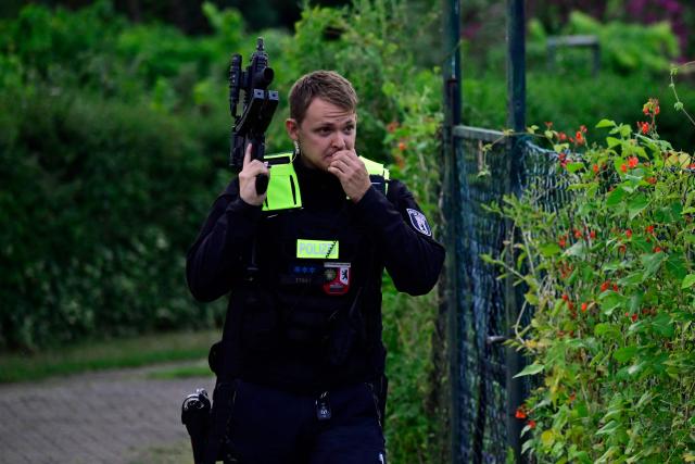 Police officers with automatic weapons walk in an allotment complex in the western Spandau district of Berlin on July 26, 2026, in a garden area near the scene where the chief suspect in the previous nights' deadly attack near Berlin's Pride parade has been shot dead. German police searched on July 26, 2026 for a suspect believed linked to Islamist circles after a car ploughed into a crowd near Berlin's Gay Pride celebrations, killing one person and wounding 16 others. The incident shattered what had been a day of celebration for hundreds of thousands attending Christopher Street Day, one of Europe's largest Pride events, and left revellers fleeing a central Berlin park as sirens echoed through the night. (Photo by John MACDOUGALL / AFP)
